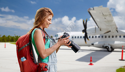 航空旅行,旅游旅行微笑的旅游妇女与背包相机飞机上的机场背景女人带着相机背包乘飞机旅行女人带着相机背包乘飞图片