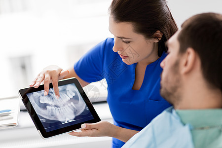 口腔医生女牙医用平板电脑病人的X光背景