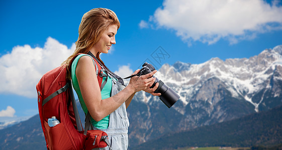 相机镜头特写旅行,旅游摄影快乐的轻妇女背包相机拍摄阿尔卑斯山背景女人带着背包相机阿尔卑斯山上女人带着背包相机阿尔背景