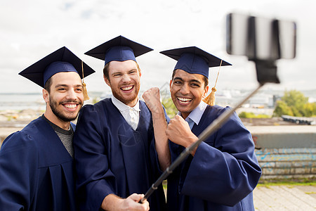 教育毕业技术成就群快乐的国际学生穿着灰浆板学士服户外自拍棒拍照庆祝快乐的男学生毕业生自拍快乐的男学背景图片