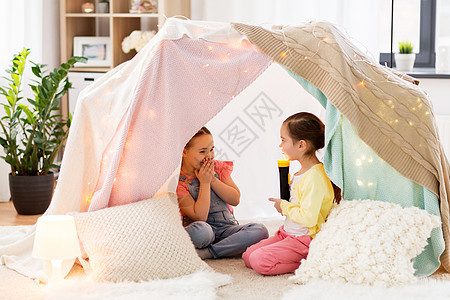 童,潮湿友谊的小女孩与火炬光孩子帐篷帐篷家里玩孩子们家里的帐篷里放着手电筒的小女孩孩子们家里的帐篷里图片