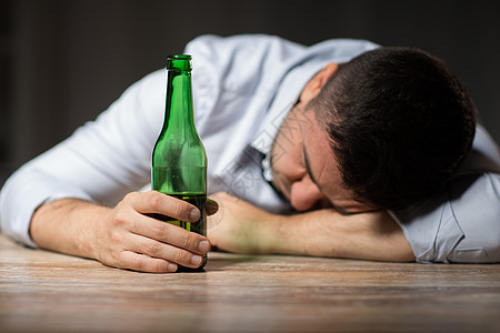 酒精中,酒精成瘾人的男酒精与啤酒瓶躺桌子上晚上睡觉喝醉了的人,晚上躺桌子上着啤酒瓶喝醉了的人,晚上躺图片