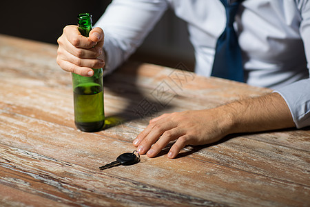 酗酒,醉酒驾驶人的男司机的手与啤酒瓶汽车钥匙桌子上用酒精汽车钥匙把手闭上用酒精汽车钥匙把手闭上图片