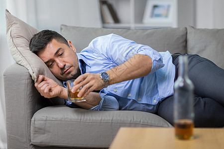 酗酒,酗酒人的男酗酒者躺沙发上喝威士忌酒鬼躺沙发上喝威士忌图片