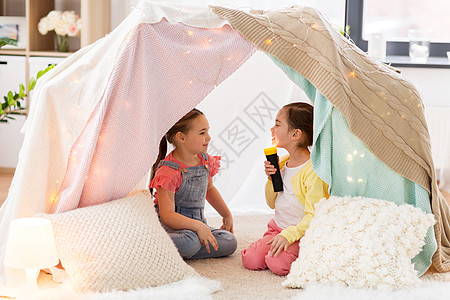 童,潮湿友谊的小女孩与火炬光孩子帐篷帐篷家里玩孩子们家里的帐篷里放着手电筒的小女孩图片