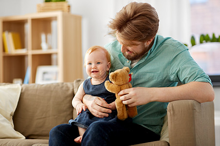 小孩背影家庭,父亲人的快乐的红头发父亲小宝贝女儿家里玩泰迪熊爸爸宝贝女儿家带着泰迪熊背景