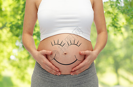怀孕,爱,人期望的密切孕妇的肚子与微笑绿色的自然背景微笑着靠近孕妇的肚子背景图片