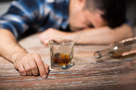 男酒精与杯威士忌瓶子躺桌子上晚上睡觉晚上桌子上喝了杯酒的醉汉图片