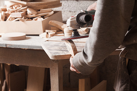 工人抛光木桌,木匠用电砂机打磨木材用于木材的砂光机图片