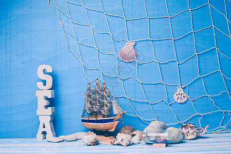 美丽的海洋成与玩具帆船,贝壳,璃瓶渔网蓝色背景海洋内部装饰图片