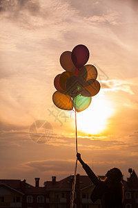 漂亮的女孩带着五颜六色的大气球镇上附近的山上散步专注于气球五颜六色气球的女孩背景