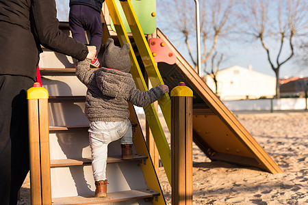 蹒跚学步的孩子玩得开心小男孩爬上个蹒跚学步的公园的楼梯图片