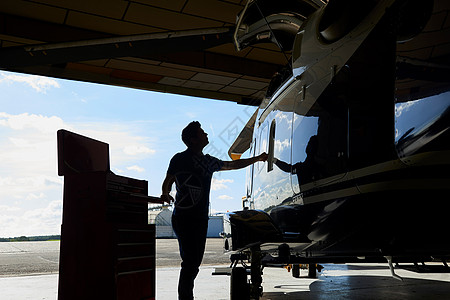 机库事直升机工作的男航空工程师的剪影图片