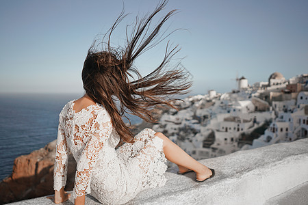 穿着白色连衣裙的快乐女人桑托里尼岛享受假期OIA看爱琴海欧洲夏季旅游目的地希腊岛屿图片