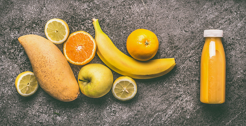 黄色机水果冰沙与柠檬,橘子,苹果,芒果香蕉瓶灰色花岗岩桌子上,顶部视图健康饮食抗氧化饮料图片