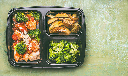 健康平衡的午餐盒,鸡肉片西红柿酱与绿色西兰花烤土豆,顶部的景观背景图片