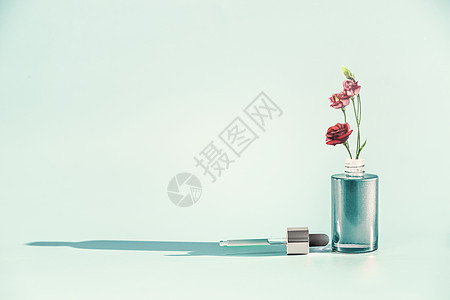 草药护肤化妆品美容理念部血清油瓶与滴管吸管花站蓝色背景,正视图现代最小的创意布局图片
