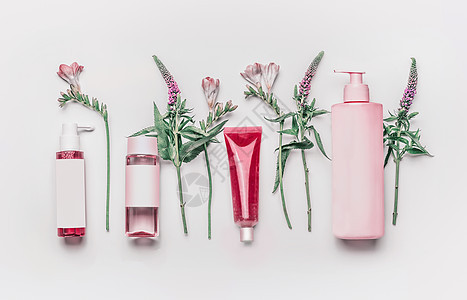 粉红色草药天然部化妆品与草药花白色背景,顶部视图品牌模拟图片