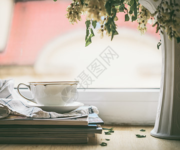 窗户上的叠杂志上放着花瓶花夏天的静物舒适的家庭场景图片