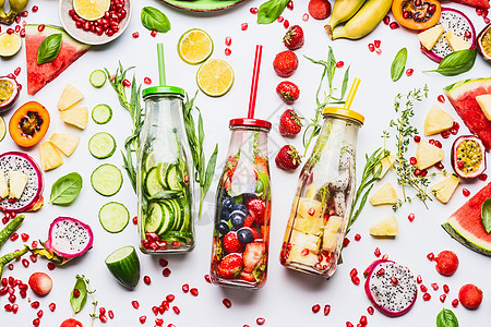 夏季清洁健康的生活方式健身背景与各种注入水瓶子,五颜六色的切片成分水果,浆果,蔬菜,草药白色背景,顶部查看图片