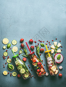 各种五颜六色的注入水的瓶子与水果浆果,黄瓜,草药饮料吸管与配料桌子上,顶部视图美味的夏季清洁饮料,健康的生活方式健身图片