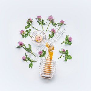 蜂蜜北斗七星与蜂蜜污渍罐子与野生三叶草花白色背景,顶部视图图片