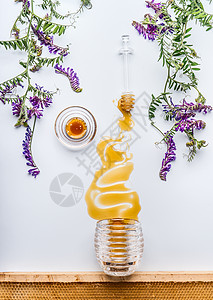 蜂蜜梳子北斗七星蜂蜜污渍罐子与野花白色背景,顶部的图片