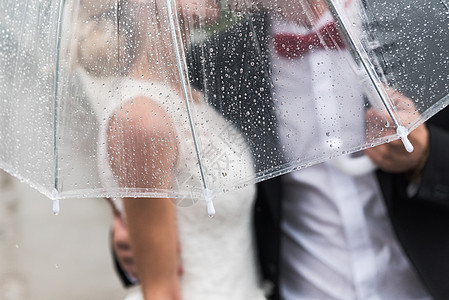 新娘新郎雨中被把透明的伞,雨滴覆盖背景图片