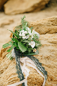 来自粪便玫瑰的新娘躺海边的砂岩石上图片