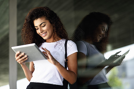 轻的黑人女子看着她的数字平板电脑户外背景图片