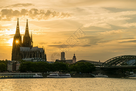 日落后,科隆大教堂的双哥特式尖顶沿霍恩佐伦桥河流游船莱茵河,德国,欧洲图片