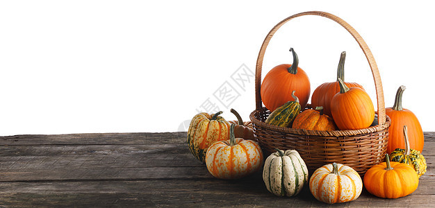 许多南瓜篮子上的木制桌子上隔离白色背景,万节感恩节的篮子里的南瓜图片