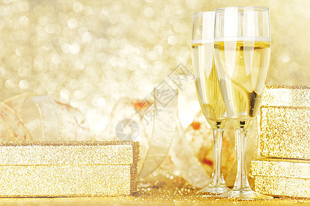 两个优雅的长笛闪闪发光的香槟与装饰金色的礼物图片