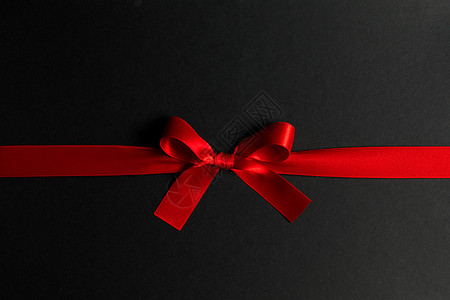 黑色背景上的红色礼物蝴蝶结红色礼物蝴蝶结黑色上图片