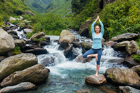 印度女人女人哈塔瑜伽平衡瑜伽,阿莎娜,vrikshasana树姿势瀑布户外瑜伽中的女人瀑布户外摆姿势背景