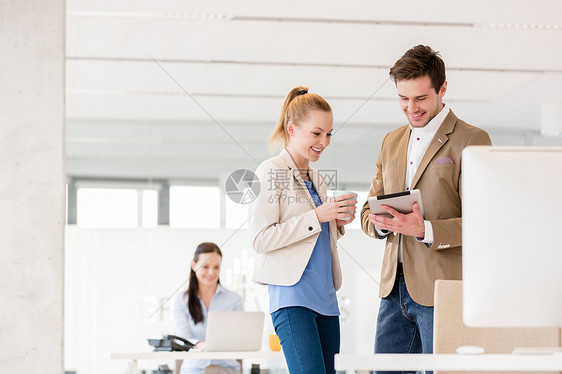 轻的女商人男同事办公室用数字平板电脑图片