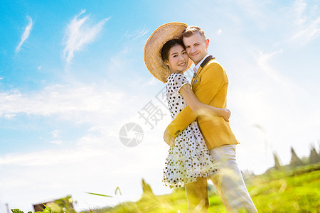 侧景肖像浪漫夫妇拥抱田野抗天空图片