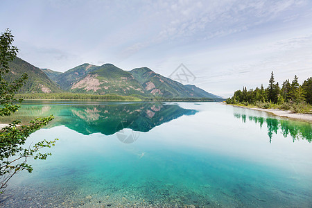 平静的景色加大的山湖旁边,岩石平静的水中反射图片