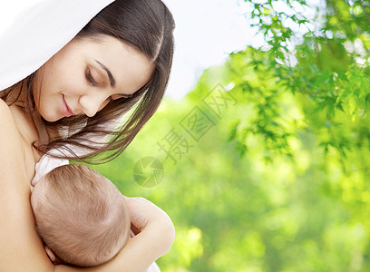 家庭,母乳喂养母亲的快乐的微笑轻母亲与小婴儿吸吮乳房绿色的自然背景母亲母乳喂养婴儿的自然背景图片