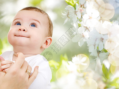 甜蜜来袭家庭,童人的亲密的甜蜜小女婴与母亲交接樱花背景用妈妈的手把可爱的小宝宝关来背景