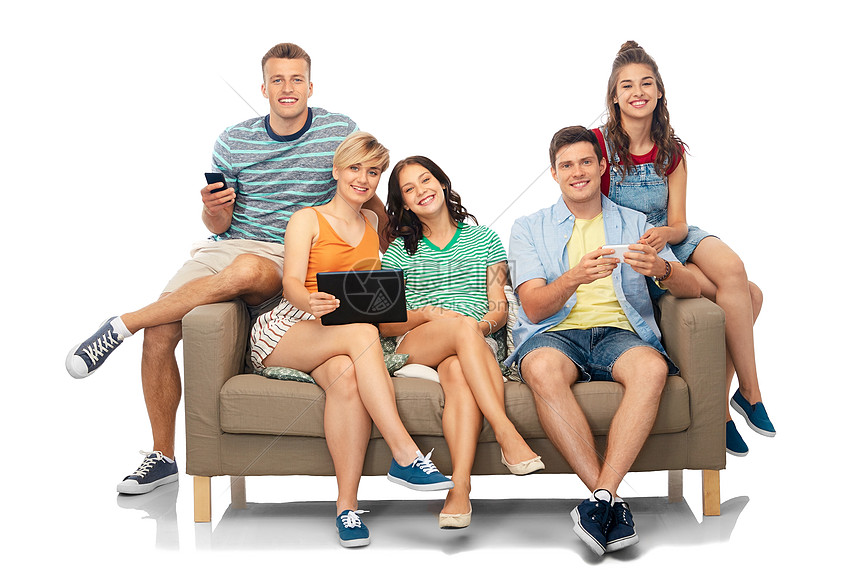 友谊休闲技术群快乐的微笑朋友与平板电脑,电脑智能手机坐沙发上的白色背景平板电脑智能手机的朋友坐沙发上图片