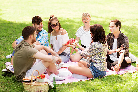 友谊休闲夏天的群快乐的朋友公园野餐时吃西瓜快乐的朋友夏天野餐时吃西瓜图片
