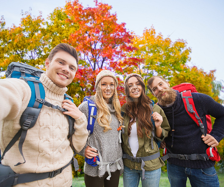 旅行,旅游,徒步旅行人的群微笑的朋友背包秋天的树木背景上自拍朋友们带着背包秋天自拍图片