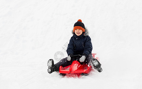 童,雪橇季节的快乐的小男孩滑雪橇下雪山冬天的户外快乐的男孩冬天乘雪橇滑下雪山图片