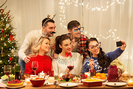 节日庆祝快乐的朋友与派道具自拍智能手机家里诞晚餐朋友们诞晚餐上自拍图片