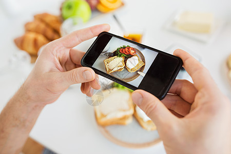 食物,饮食技术手与智能手机拍摄早餐盘子上用智能手机拍照食物的手图片
