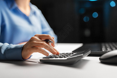 商业,财务会计女商人与计算器计数填写税务表格夜间办公室带计算器的女商人夜间办公室背景图片