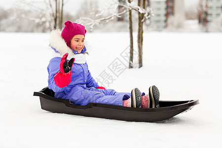 童,雪橇季节快乐的小女孩穿着雪衣坐雪橇户外冬天冬天户外雪橇上快乐的小女孩图片