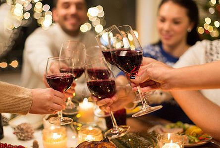 节日庆祝亲密的快乐朋友家里吃诞晚餐,喝红酒碰杯亲密的朋友用葡萄酒庆祝诞节背景图片