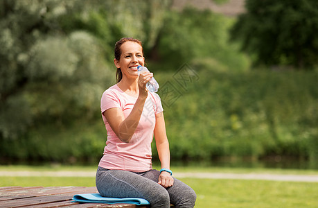 运动健康的生活方式妇女与健身跟踪器饮用水后,公园锻炼妇女公园锻炼后喝水图片